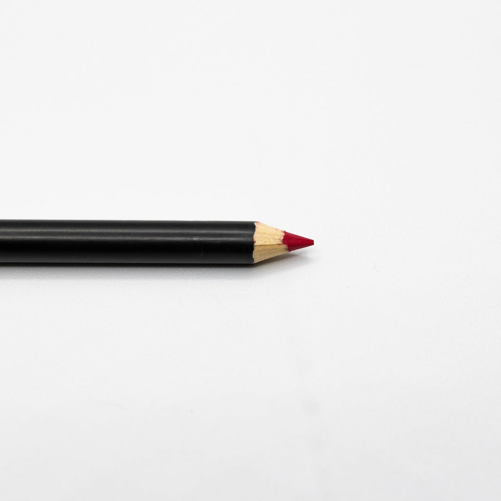 An Espoir Studios RED LIP LINER PREDRAW PENCIL with a sharpened red tip, perfect for lip mapping, lies on a white surface.